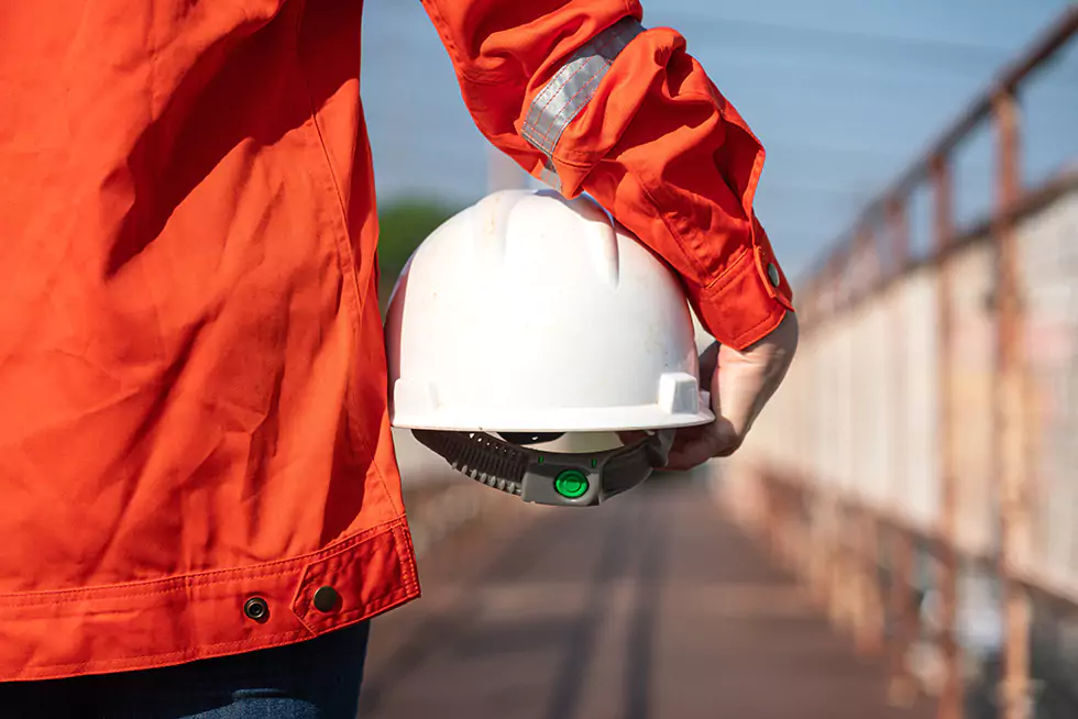 Nahaufnahme eines Bauarbeiters, der einen Schutzhelm in der Hand hält